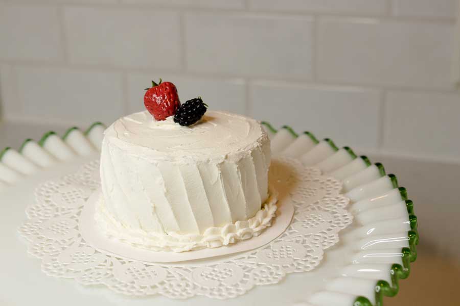 faux cake iced in faux vanilla icing and topped with faux berries