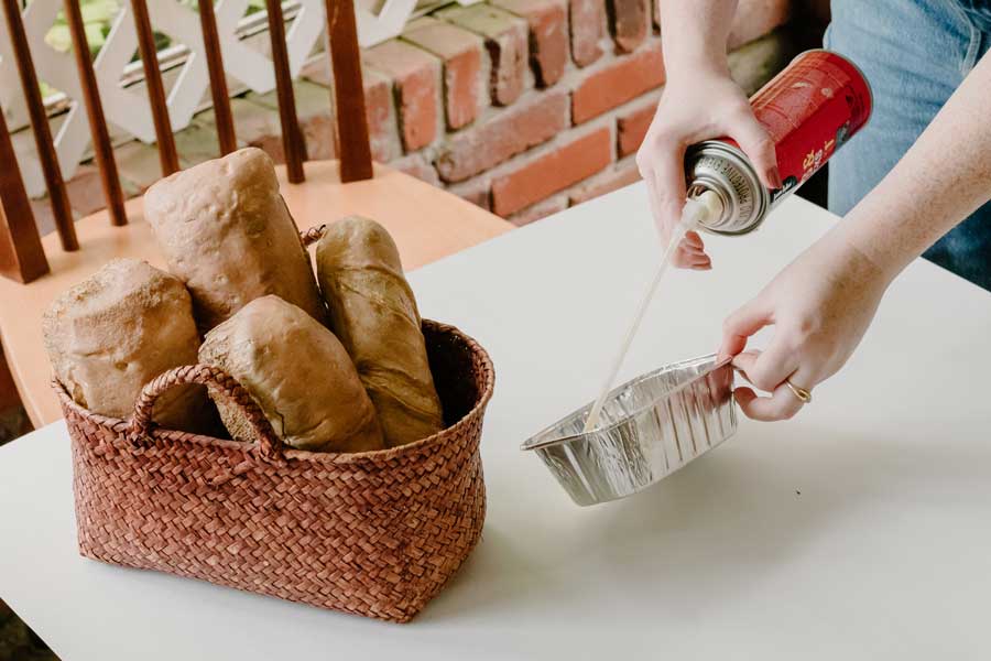 hands spraying spray foam into a bread tin