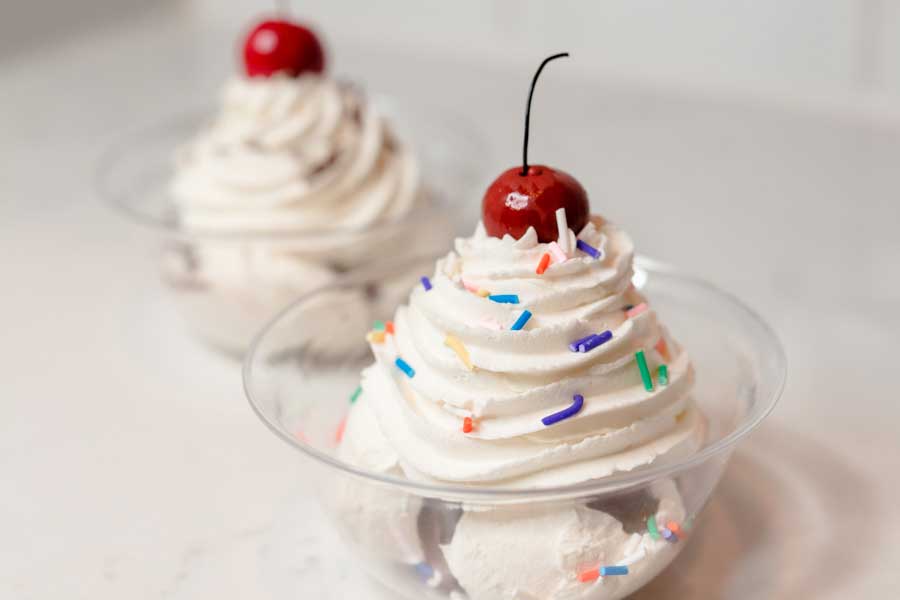 faux ice cream sundae with whipped cream, multi-colored sprinkles, and a red faux cheery on top