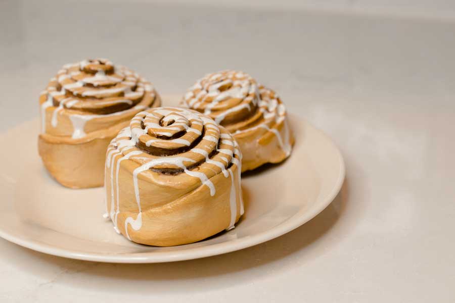a plate of three faux cinnamon rolls covered in faux white icing